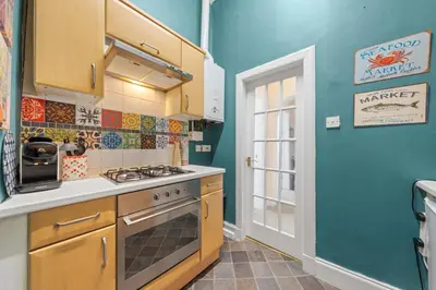 a kitchen with blue walls and a stove top oven at Cosy 1 Bedroom Apartment next to Fountain Park - Edinburgh in Edinburgh