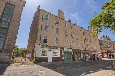 a large brick building on a city street at Cosy 1 Bedroom Apartment next to Fountain Park - Edinburgh in Edinburgh