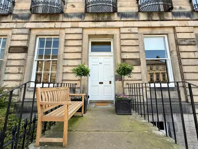 a wooden bench sitting in front of a building at New Town luxury 1 bed apartment in Edinburgh