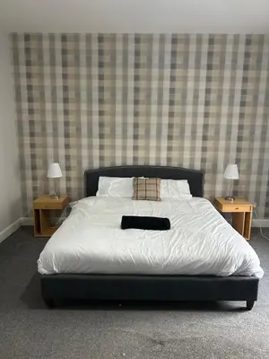 a bed in a room with two nightstands and two lamps at The Seaport Apartnment in Greenock