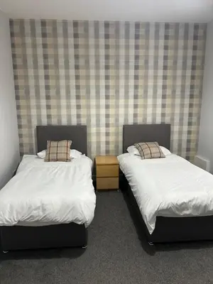 two beds sitting in a room withskirts at The Seaport Apartnment in Greenock