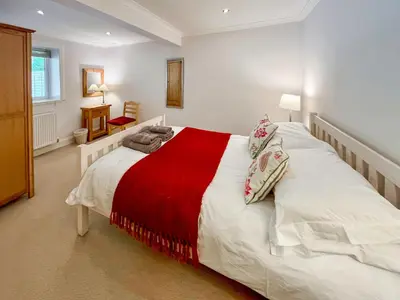 a bedroom with a large white bed with a red blanket at Riverview Cottage in Kenmore