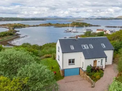 an aerial view of a house on the shore of a body of water at Memorising sea views contemporary, spacious 4 bedroom coastal villa near Oban in Craobh Haven