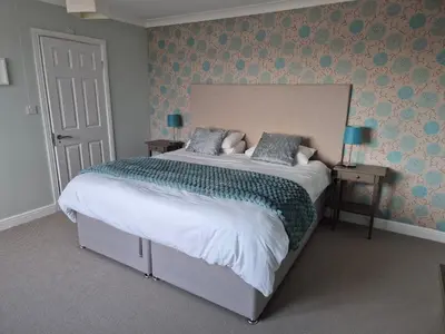 a bedroom with a large bed with blue wallpaper at Memorising sea views contemporary, spacious 4 bedroom coastal villa near Oban in Craobh Haven