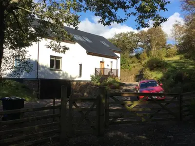 a white house with a red car parked in front of it at Memorising sea views contemporary, spacious 4 bedroom coastal villa near Oban in Craobh Haven