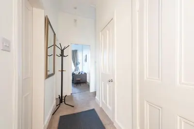 a hallway with white walls and a black rug at Cosy 2-bedroom Edinburgh flat close to city centre in Edinburgh