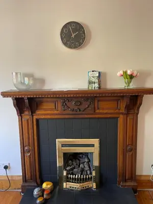 a fireplace with a clock on top of it at Charming flat in beautiful area in Edinburgh