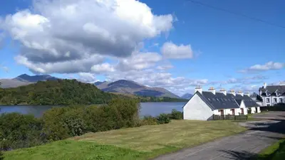 a house on the side of a lake with mountains at Inveraray, Loch Awe Rooms and Apartments in Portsonachan