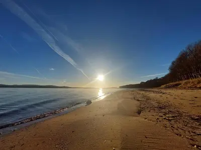 a beach with the sun shining on the water at 2 Bed Flat - Sleeps 4 - Pets - Parking - Wifi in Rothesay