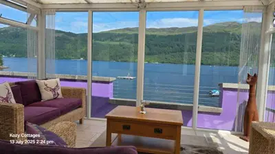 a living room with a large view of a lake at Jenny's Bay with Hot Tub in Lochgoilhead