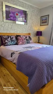a bed with a purple comforter in a bedroom at Jenny's Bay with Hot Tub in Lochgoilhead