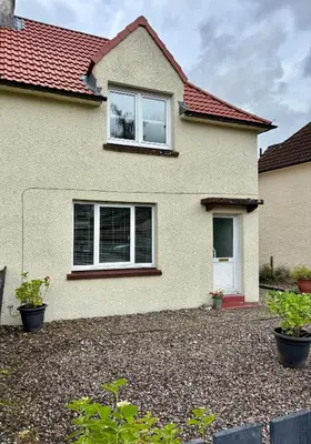 a house with two windows and a gravel driveway at West Highland Hideaway in Kinlochleven
