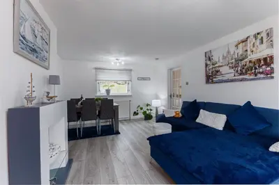 a living room with a blue couch and a table at Comfortable & cozy Home Stay in East Kilbride
