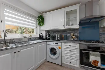 a kitchen with white cabinets and a washer and dryer at Comfortable & cozy Home Stay in East Kilbride