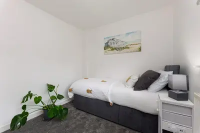 a bedroom with a bed with white walls at Comfortable & cozy Home Stay in East Kilbride