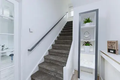 a staircase in a home with white walls and white stairs with plants at Comfortable & cozy Home Stay in East Kilbride