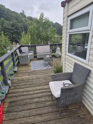 a deck with wicker chairs and tables on a house at Shep2 Caravans in Ballantrae