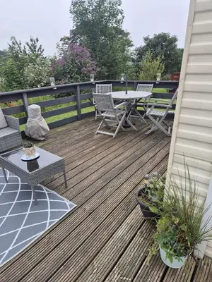 a wooden deck with a table and chairs on it at Shep2 Caravans in Ballantrae