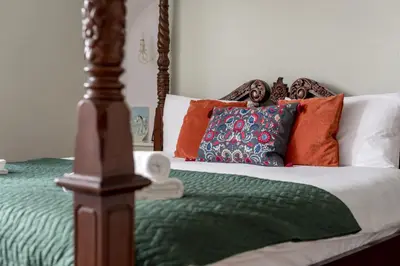 a bed with a green comforter and orange pillows at Double Edinburgh Homestay in Edinburgh