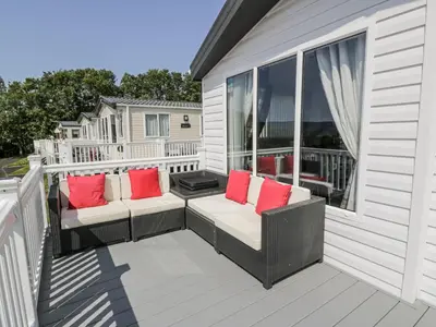 a porch with two wicker chairs with red pillows at Manor Heights Lodge in Wemyss Bay