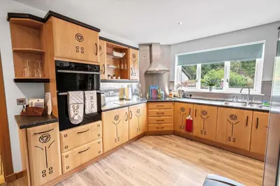 a large kitchen with wooden cabinets and a window at Spacious 4BD Home with Stunning Oban Views in Oban
