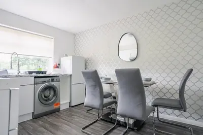 a kitchen with a table and chairs and a washing machine at 3 BDR House By Caledonia Luxe Stays Short Lets & Serviced Accommodation West Calder in West Calder