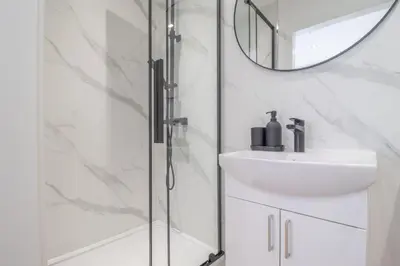 a bathroom with a shower and a sink and a mirror at Alexandra Apartment in Falkirk