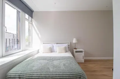 a white bedroom with a bed and a window at Alexandra Apartment in Falkirk