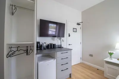 a kitchen with white cabinets and a tv on the wall at Alexandra Apartment in Falkirk