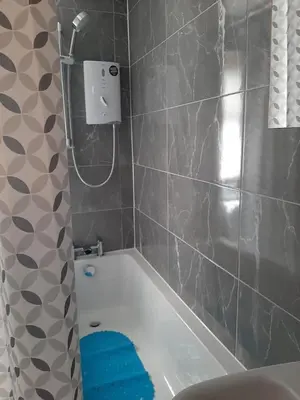 a bathroom with a white bath tub and a blue towel at Newly renovated & furnished luxury bedroom in Kirkliston
