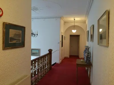 a hallway of a house with a staircase and paintings at Limefield Mansion House in Livingston