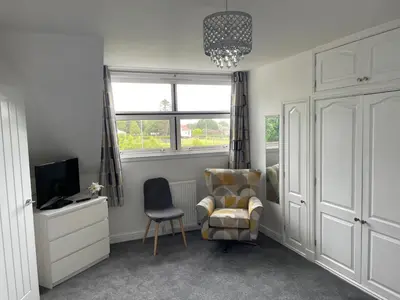 a bedroom with a chair and a tv and a window at The Stables in Symington in Symington