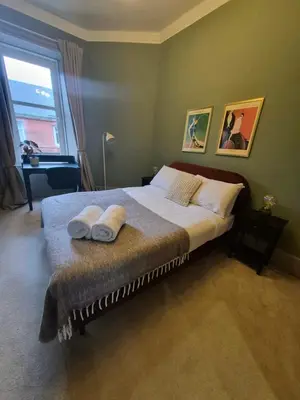 a bedroom with a bed with two towels on it at Townhead Jewel by Coorie Doon Stays in Paisley