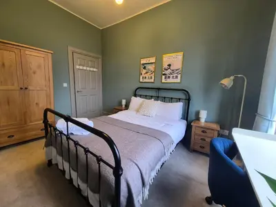 a bedroom with a bed and a table and a lamp at Townhead Jewel by Coorie Doon Stays in Paisley