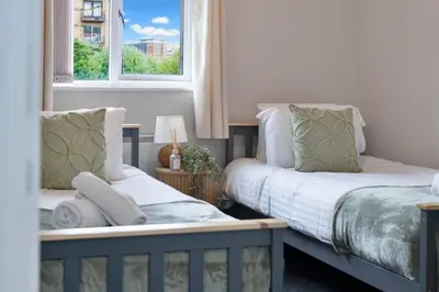 two beds in a room with two windows at Riverside City Apartment in Glasgow