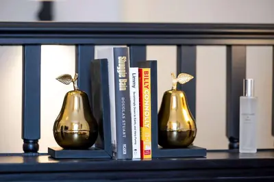 a shelf with books and gold vases on it at Luxury Refurbished City Retreat in Glasgow