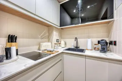 a kitchen with white cabinets and a sink at Luxury Refurbished City Retreat in Glasgow