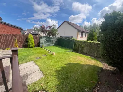 a backyard with a fence and a grass yard at Bespoke home in Kirky in Kirknewton