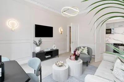 a white living room with a couch and a tv at The Compact Caledonian Flat - Haymarket in Edinburgh