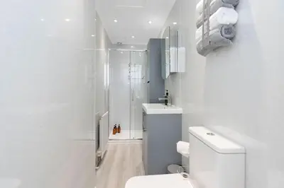 a white bathroom with a shower and a toilet at The Compact Caledonian Flat - Haymarket in Edinburgh