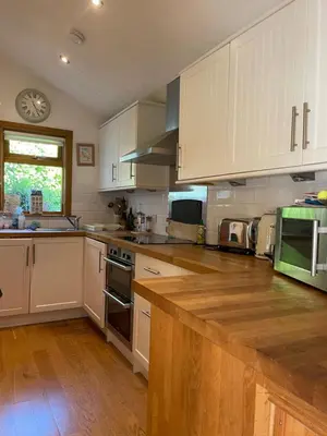 a kitchen with white cabinets and a wooden counter top at Grey Gables Cottage, Brodick, Isle of Arran, Scotland in Isle of Arran