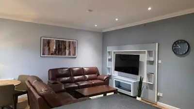 a living room with a leather couch and a television at ANSI Splendor in Livingston