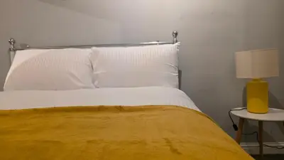 a bedroom with a bed with a yellow lamp on a table at ANSI Splendor in Livingston
