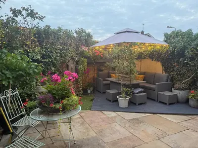 a patio with chairs and an umbrella and flowers at The Rookery in Moffat