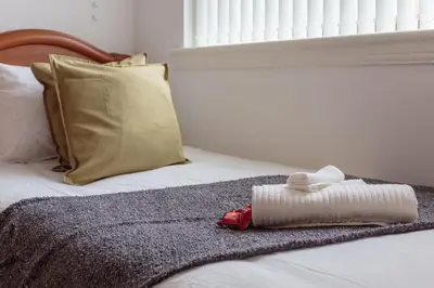 a bed with a rolled up towel on it at Free Parking - City Centre - 3 Bedrooms - 5 Guests in Edinburgh