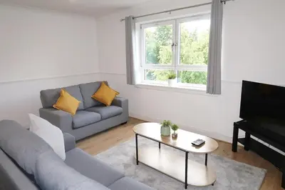 a living room with a couch and a table and a television at Spacious 2 Bed Apartment Near Glasgow Airport in Glasgow