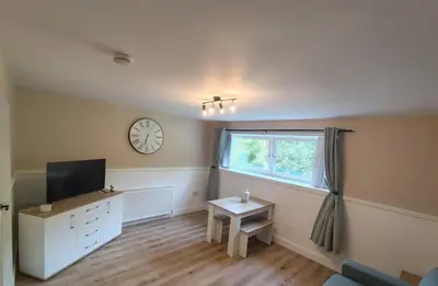 a living room with a tv and a clock on the wall at Millburn Chalet in Inverkip