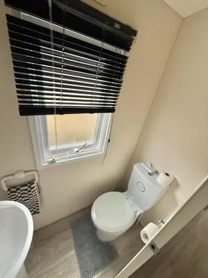 a bathroom with a toilet and a sink and a window at Four-bed Delta Caravan, Uddingston, Glasgow Located in Uddingston, Glasgow at Maryville Caravan Site in Uddingston