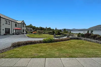 a house with a large yard next to the water at The Allanbreck Studio Glencoe Ballachulish Highlands Near Fortwilliam in Glencoe