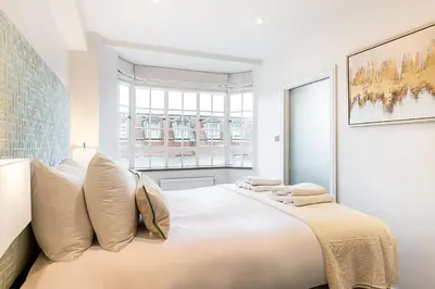 a white bedroom with a large bed with pillows at Stylish Chelsea Flat Near Sloane Square in Moffat